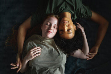 Multiracial Homosexual couple lying cheek to cheek on the bed with their eyes closed. LGBT gender diversity concept.