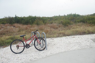 Obraz premium Red Bicycle Parked in Front of Sand Dune at the Beach