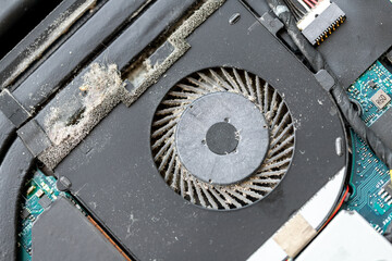 Close-up detail view of disassembled laptop pc motherboatd with dirty dust chip gpu cooling fan part. Fixing computer overheating. Professional Tech and electronics service fix repair maintenance