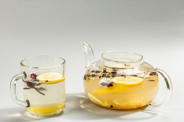 Hot ginger tea with lemon and honey in a glass cup on light grey background