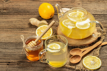 Hot ginger tea with lemon and honey in a glass cup on a wooden boards background