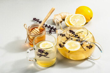 Hot ginger tea with lemon and honey in a glass cup on light grey background