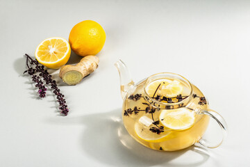 Hot ginger tea with lemon and honey in a glass cup on light grey background
