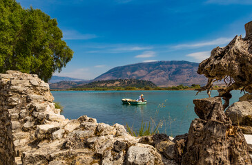 An albanian fisherman in his boat on Butrint lake salt lagoon, view from Butrint National Park, the...