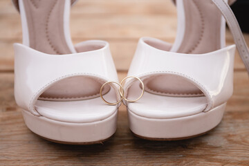 Engagement rings on a wooden background in front of the shoes