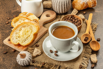 Breakfast concept with a cup of coffee, croissants, milk jug, and decorative crochet pumpkins