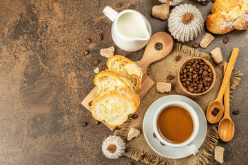 Breakfast concept with a cup of coffee, croissants, milk jug, and decorative crochet pumpkins