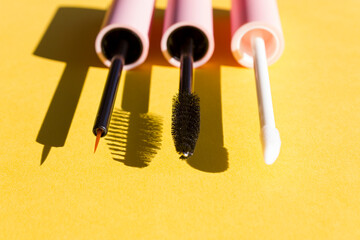 Makeup brushes on a bright yellow background with sharp shadows of sun. Cosmetics application and face care concept. Close up. Copy space.