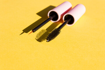 Makeup brushes on a bright yellow background with sharp shadows of sun. Cosmetics application and...