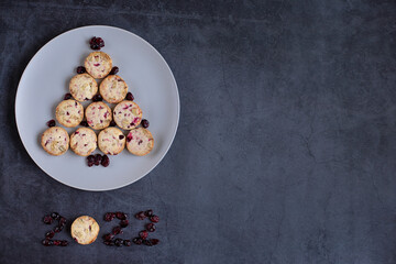 Cute edible Christmas tree made of cookies on a round plate on a grey dark background. Creative tree, figures 2022. Space for design and text. Concept holidays, pastries, New Year