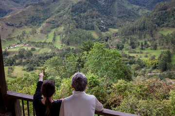 Senior mother and adult daughter traveling together at the beautiful view point over the Cocora Valley at Salento, located on the region of Quindio in Colombia