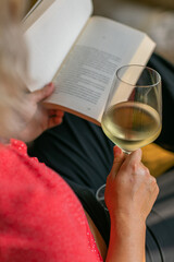 Chica leyendo libro con copa de vino en la mano 