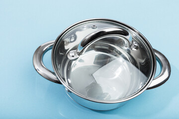 steel pan with a transparent lid on blue background .