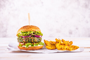 Vegan burger with potato wedges on a white table and with a white background. Vegetable meat. Ready to eat. 