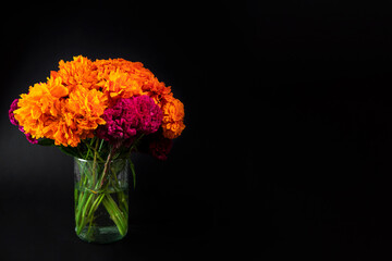 Florero de día de muertos con flores de cempasúchil con fondo negro.