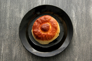 Fresh, delicious and freshly made sweet bisquet bread ready to eat on a wooden table with a colored napkin accompanied by hot coffee for breakfast
