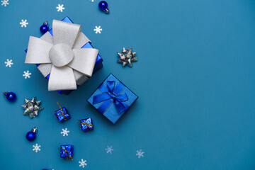 Winter background blue. Cute gift box with blue ribbon, christmas balls in a christmas composition of snowflakes on a blue background for a greeting card. Christmas, winter, new year concept