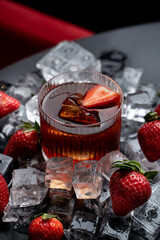 Juicy strawberry alcoholic cocktail surrounded with ice cubes and berries, commercial photography