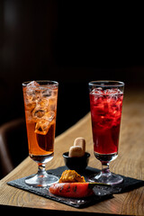 Two posh and elegant cocktails in an expensive bar on a wooden bar counter, dark photo, muffled light