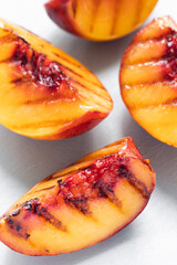 Juicy grilled nectarine quarters on light gray cutting board. Top view. Selective soft focus. Abstract food background.