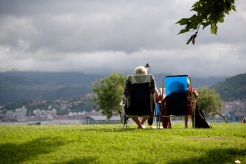 Dos señoras de espaldas sentadas en unas sillas de playa en un campo verde