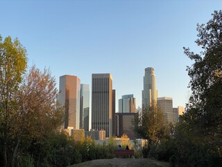 LOS ANGELES, CA, JAN 2021: Downtown skyline with skyscrapers seen from park to the north of the city, people silhouetted on bench in foreground