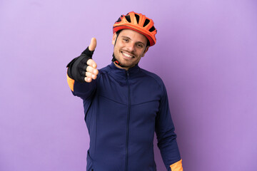 Young Brazilian cyclist man isolated on purple background shaking hands for closing a good deal