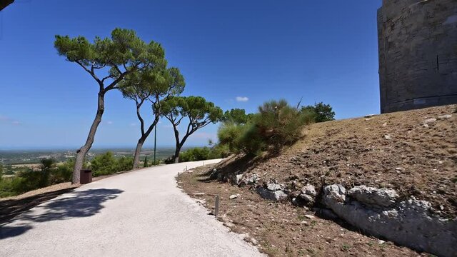Andria, Puglia, Italy. August 2021. POV footage walking around Castel del Monte. On the right the imposing walls of the castle on the left the amazing landscape of the Murgia park.
