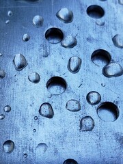 water droplets on a metal plate with holes, close-up. Macro photo