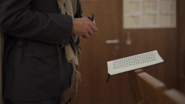 A Jew prays while standing, side view.