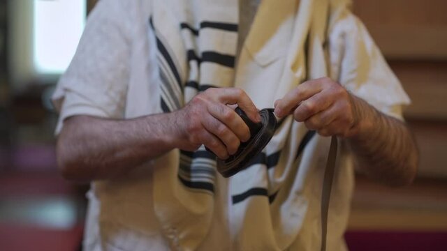 An adult man, a Jew, folding tefillin.