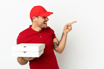 pizza delivery man with work uniform picking up pizza boxes over isolated  white wall pointing...