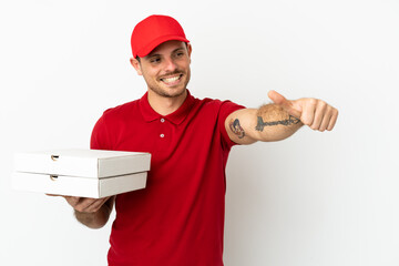 pizza delivery man with work uniform picking up pizza boxes over isolated  white wall giving a...