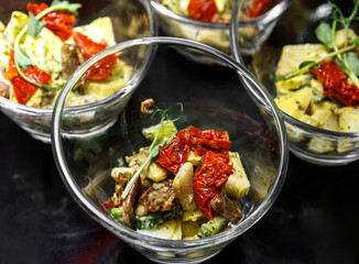 A light snack of potatoes, cucumbers, chili peppers, chicken meat and herbs in transparent serving cups.