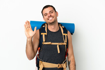 Brazilian mountaineer man with a big backpack over isolated white background saluting with hand with happy expression