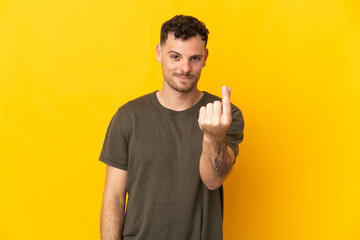 Young caucasian handsome man isolated on yellow background making money gesture