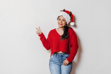 cheerful young latinx woman look at camera doing victory sign, peace concept.