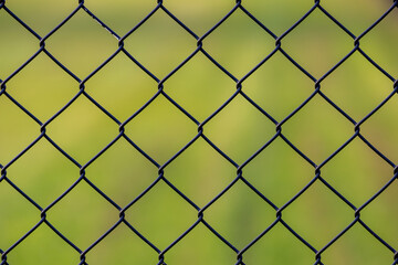 Abstract background, Old metal fence with wire mesh, Steel iron mesh net cage in the garden with green grass as backdrop.