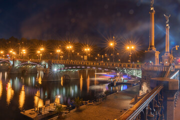 Fototapeta na wymiar Bridge across Vltava River illuminated at night with lighting reflected in water