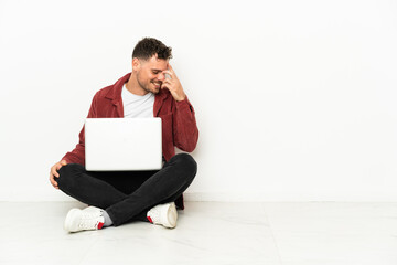 Young handsome caucasian man sit-in on the floor with laptop laughing