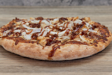 Freshly baked BBQ chicken pizza with chopped meat toppings served on a wooden platter