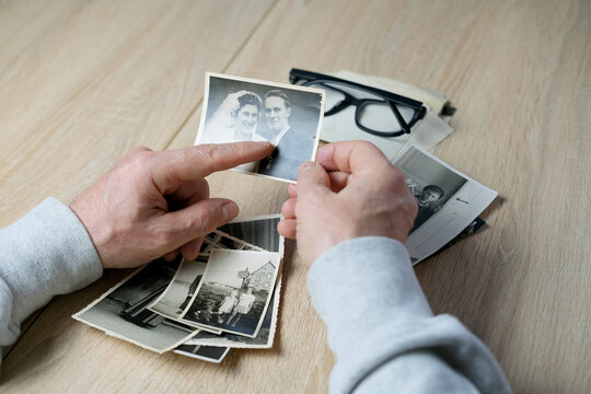 an elderly man looks through his old photographs of 1960-1965, the concept of nostalgia and memories of youth, childhood, remembering his life, relatives, family connection of generations