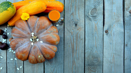 Pumpkins with zucchini on a wooden background. A glass of juice and pumpkin seeds. Natural background with pumpkins for Halloween.