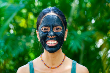 Happy woman with charcoal facemask 