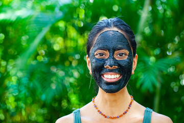 Happy woman with charcoal facemask 