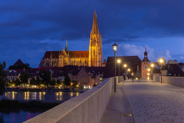 Regensburg. Old stone bridge over the Danube river in the night light.