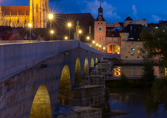 Fototapeta na wymiar Regensburg. Old stone bridge over the Danube river in the night light.
