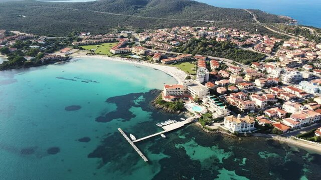 the picturesque coastal village of Golfo Aranci in northern Sardinia. perfect for vacations, beautiful beaches, clear blue water. Boats anchored on the jetty. drone aerial circeling view, Italy.