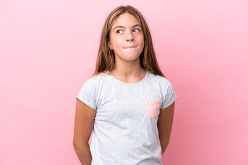 Obraz premium Little caucasian girl isolated on pink background having doubts while looking up