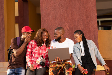 group of black college students gathering around a laptop